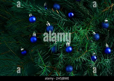 Sfondo verde di Natale. Rami di pino, aghi e alberi di Natale con palline blu. Vista dall'alto. Cornice rotonda con la posizione per il testo. Sfondo natura di Natale. Concetto di umore di dicembre. Foto Stock
