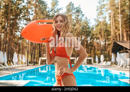 Bagnino femminile in un costume da bagno rosso accanto alla piscina pubblica Foto Stock