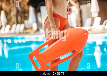 Bagnino femminile in un costume da bagno rosso accanto alla piscina pubblica Foto Stock
