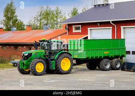 Trattore John Deere 6155R di fronte al rimorchio Palmse 1900 presso il cortile dell'azienda agricola il giorno dell'inizio dell'autunno. Salo, Finlandia. Agosto 29, 2020. Foto Stock