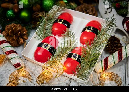 Dessert rosso di Natale in forma di mousse sullo sfondo di candele, ghirlande, rami di abete e coni Foto Stock