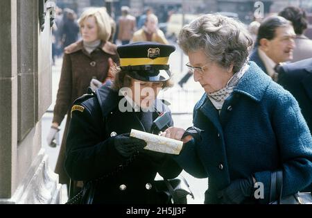 Londra 1982. Una vista sulla strada di Londra e un guardiano del traffico cercando di aiutare una signora anziana a trovare la sua strada. Ha una mappa ed entrambi la stanno guardando. Credit Roland Palm. Foto Stock