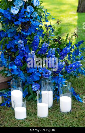 Arch per una cerimonia nuziale di fiori freschi in blu, e candele, primo piano. Decorazioni per matrimoni. Messa a fuoco selettiva soft. Foto Stock