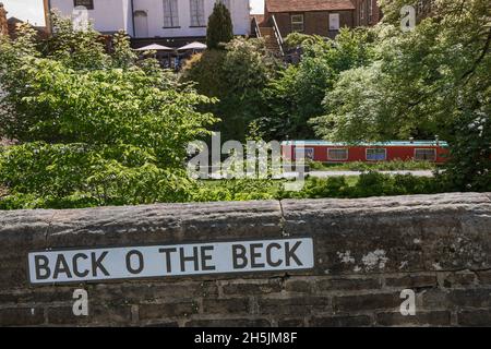 Sul retro del Beck Skipton, in estate si può vedere un cartello che conduce ad un piccolo torrente boschivo che corre accanto al Springs Branch Canal a Skipton, Yorkshire UK Foto Stock