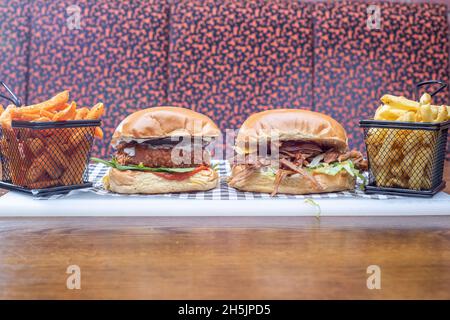 Sheffield UK – 22 maggio 2018: Hamburger di maiale e hamburger di pollo con patatine fritte regolari o dolci – cibo americano da pranzo da Fire Pit, West Street Foto Stock