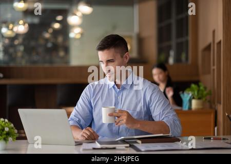 un uomo d'affari sorridente che ha una chiamata a riunione virtuale, una conversazione, un lavoro in remoto a casa guardando il webinar di formazione online in ufficio remoto Foto Stock