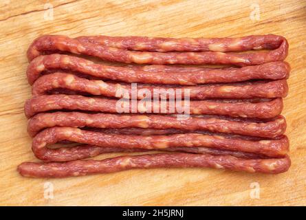 salsiccia affumicata sottile per birra su sfondo di legno. Snack alla birra Foto Stock