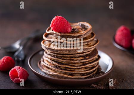 Pancake al cioccolato vegan carruba con lamponi su un piatto, vista sul primo piano Foto Stock