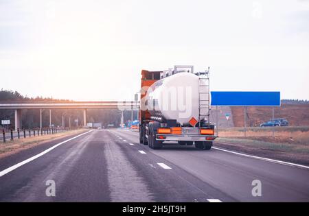 camion con semirimorchio cisterna trasporta merci pericolose in autostrada sullo sfondo del tramonto, industria. Spazio di copia per testo, petrolio Foto Stock