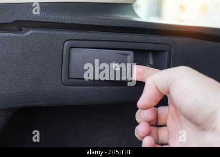 Pulsante per ripiegare e dispiegare la fila posteriore dei sedili di un'autovettura, primo piano. Automobile Foto Stock