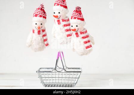 Anno nuovo, concetto di vendite natalizie. I pupazzi di neve di Capodanno vicino al cestino dello shopping su sfondo bianco. Foto Stock