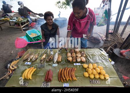 Donne che vendono alimenti tradizionali in uno stand in un mercato all'aperto a Madang, Papua Nuova Guinea; Madang, Provincia di Madang, Papua Nuova Guinea Foto Stock