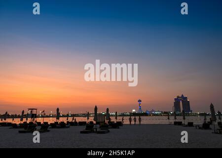 Un Beach club sotto il sole tramontante nel Golfo Persico con vista di Marina Island; Abu Dhabi, Emirati Arabi Uniti Foto Stock