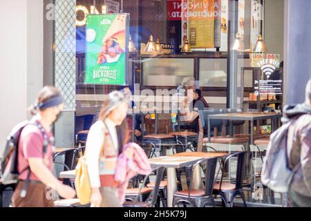 Posti a sedere vuoti sono visti all'esterno di un ristorante dove le persone sono viste all'interno di Londra mentre ristoranti e caffè sono autorizzati ad accogliere i clienti all'interno. Foto Stock