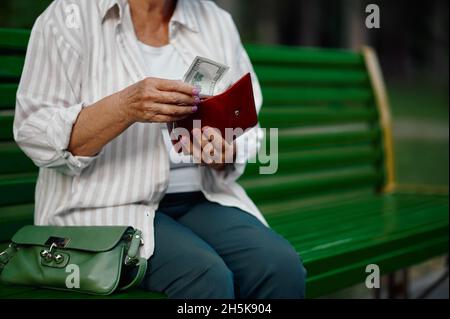 Granny prende soldi dal suo portafoglio in parco Foto Stock