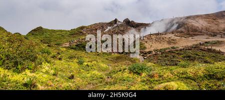 Persone che camminano lungo il sentiero di montagna vicino alla cima della Grande Soufriere con il suo cratere che emette gas, basse-Terre Foto Stock