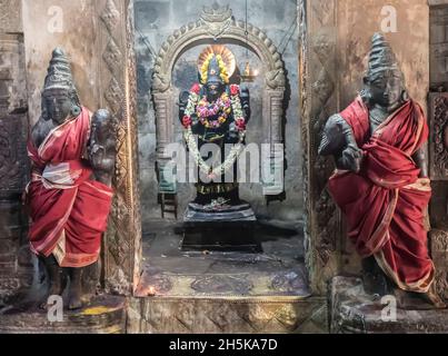 Alcova con statua della divinità indù in parete con statue guardiane avvolte in seta su entrambi i lati al Tempio di Airavatesvara dell'era Dravidiana di Chola Foto Stock