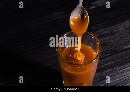 Salsa di caramello salata fatta in casa in un vaso su sfondo scuro. Copia spazio testo Foto Stock