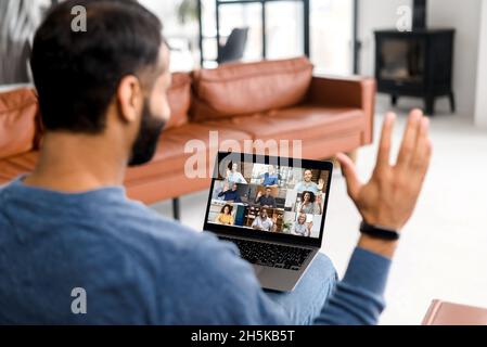 Chat video con colleghi multirazziali. Ragazzo indiano che sventolano hi, gruppo di saluto di persone durante il video meeting online, video connettersi con colleghi multirazziale. Guarda il webinar "Guy coinvolto" Foto Stock