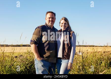 Ritratto di una coppia matura in piedi sul loro terreno agricolo; Alcomdale, Alberta, Canada Foto Stock