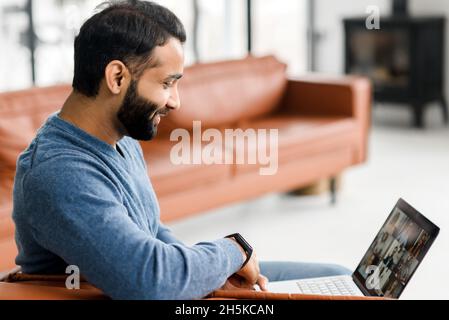 Incontro mattutino in lontananza. Uomo indiano che utilizza l'app per computer per connettersi video con un gruppo di colleghi diversi. Tipo multirazziale prendere parte a seminario educativo, webinar coinvolto Foto Stock