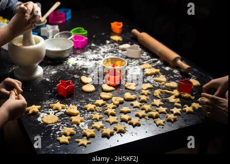 I bambini preparano biscotti di compleanno a forma di stella su un tavolo da cucina scuro. Attività congiunta della famiglia in cucina a casa. Vista dall'alto. Foto Stock