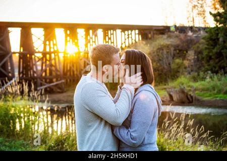 Una coppia di adulti medio che condivide un momento intimo al tramonto in un parco in autunno; St. Albert, Alberta, Canada Foto Stock