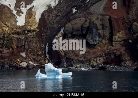 Un iceberg passato la roccia vulcanica. Foto Stock