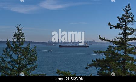 Splendida vista su Burrard Inlet con lo skyline di Vancouver, British Columbia, Canada sotto il Monte Rainer e navi da carico nella baia. Foto Stock