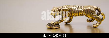 Banner con figura in bronzo di una tigre con una moneta - il simbolo del nuovo anno cinese 2022 su sfondo dorato, spazio copia. Auguri di buona fortuna, fi Foto Stock