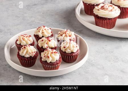 mini cupcake di velluto rosso in un piatto bianco su sfondo chiaro Foto Stock