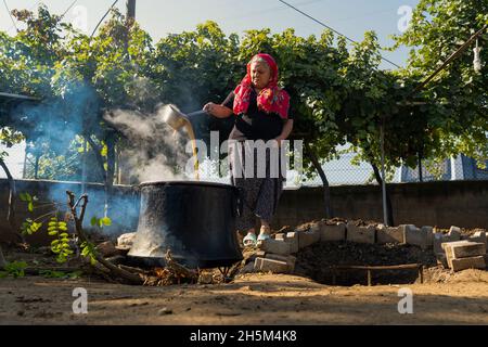 Ankara, Turchia - Settembre 18 2021: La melassa viene prodotta facendo bollire l'uva alle alte temperature nei cavoldri. La donna produce melassa (pekmez in turco). Foto Stock