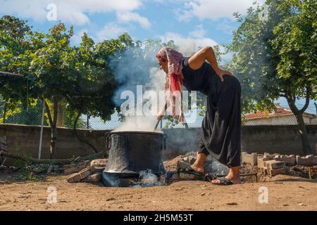 Ankara, Turchia - Settembre 18 2021: La melassa viene prodotta facendo bollire l'uva alle alte temperature nei cavoldri. La donna produce melassa (pekmez in turco). Foto Stock