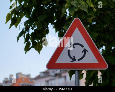 Primo piano di un triangolo rosso avvertimento rotonda segno attaccato su un palo Foto Stock