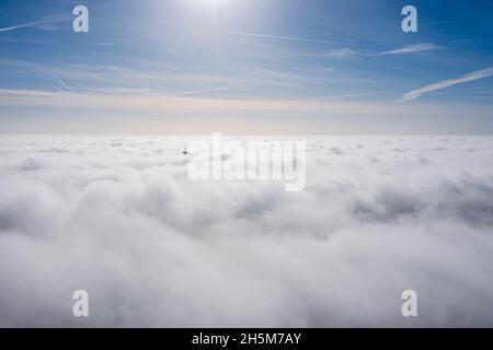Parchi eolici che sporgono sopra le nuvole, vista aerea di eliche a turbina lontane Foto Stock