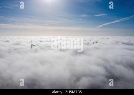 Parchi eolici che sporgono sopra le nuvole, vista aerea di eliche a turbina lontane Foto Stock