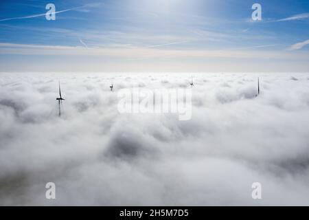 Parchi eolici che sporgono sopra le nuvole, vista aerea di eliche a turbina lontane Foto Stock