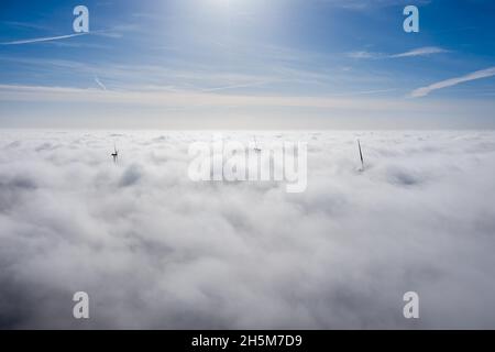 Parchi eolici che sporgono sopra le nuvole, vista aerea di eliche a turbina lontane Foto Stock