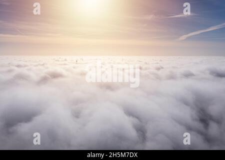 Parchi eolici che sporgono sopra le nuvole, vista aerea di eliche a turbina lontane Foto Stock