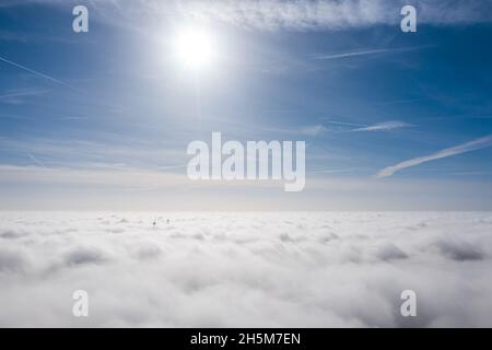 Parchi eolici che sporgono sopra le nuvole, vista aerea di eliche a turbina lontane Foto Stock