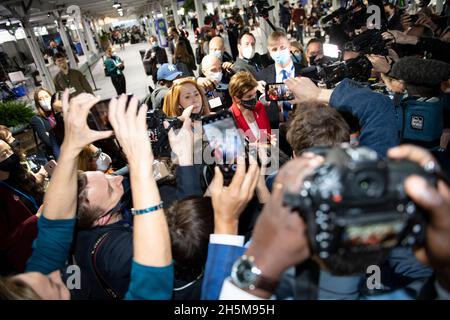 Glasgow, Regno Unito. 10th Nov 2021. Glasgow, Scozia, Regno Unito. 10 novembre 2021. NELLA FOTO: Nicola Sturgeon MSP - primo Ministro della Scozia, avvistato nel foyer alla Conferenza sul cambiamento climatico del COP26 visto nel foyer come media pack la circondano con telecamere dal vivo, fotografi e giornalisti. Notate che il suo assistente personale (visto sulla sinistra del primo Ministro nell'immagine in capelli rossi) ha la sua maschera facciale che non copre il suo volto che sembra essere in violazione delle norme COVID. Credit: Colin Fisher/Alamy Live News Foto Stock