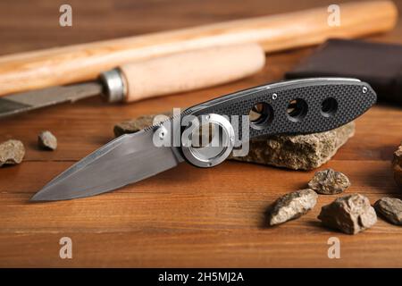 Coltello tascabile pieghevole con manico in gomma su tavolo in legno Foto Stock