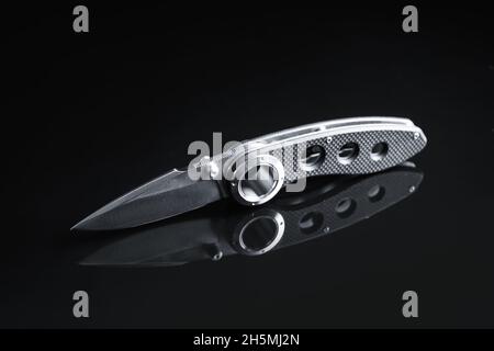 Coltello tascabile pieghevole con manico in gomma su sfondo nero Foto Stock