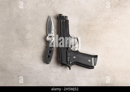 Coltello tascabile pieghevole e pistola sul tavolo Foto Stock