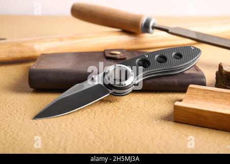 Coltello tascabile pieghevole con manico in gomma sul tavolo Foto Stock