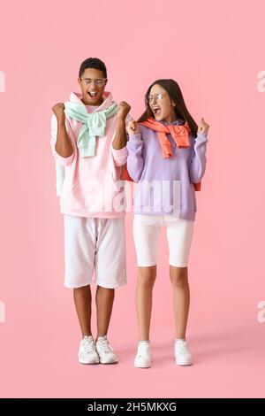 Emozionale giovane coppia in felpa con cappuccio su sfondo rosa Foto Stock