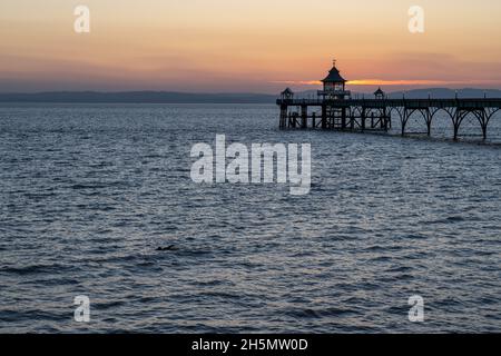 Un bagno nuota nel canale di Bristol accanto al molo di Clevedon al tramonto nel Somerset. Foto Stock