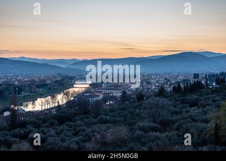 Il sole sorge lungo il fiume Arno e la periferia di Firenze, con le colline Fiesolean fornendo uno sfondo. Foto Stock