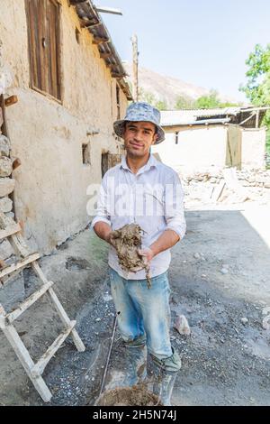 Mavzoley Rudaki, Provincia di Sughd, Tagikistan. Agosto 17, 2021. Lavoratore che applica intonaco di fango ad una casa di pietra tradizionale. Foto Stock