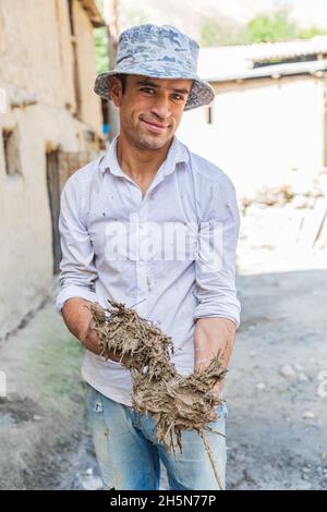 Mavzoley Rudaki, Provincia di Sughd, Tagikistan. Agosto 17, 2021. Lavoratore che applica intonaco di fango ad una casa di pietra tradizionale. Foto Stock